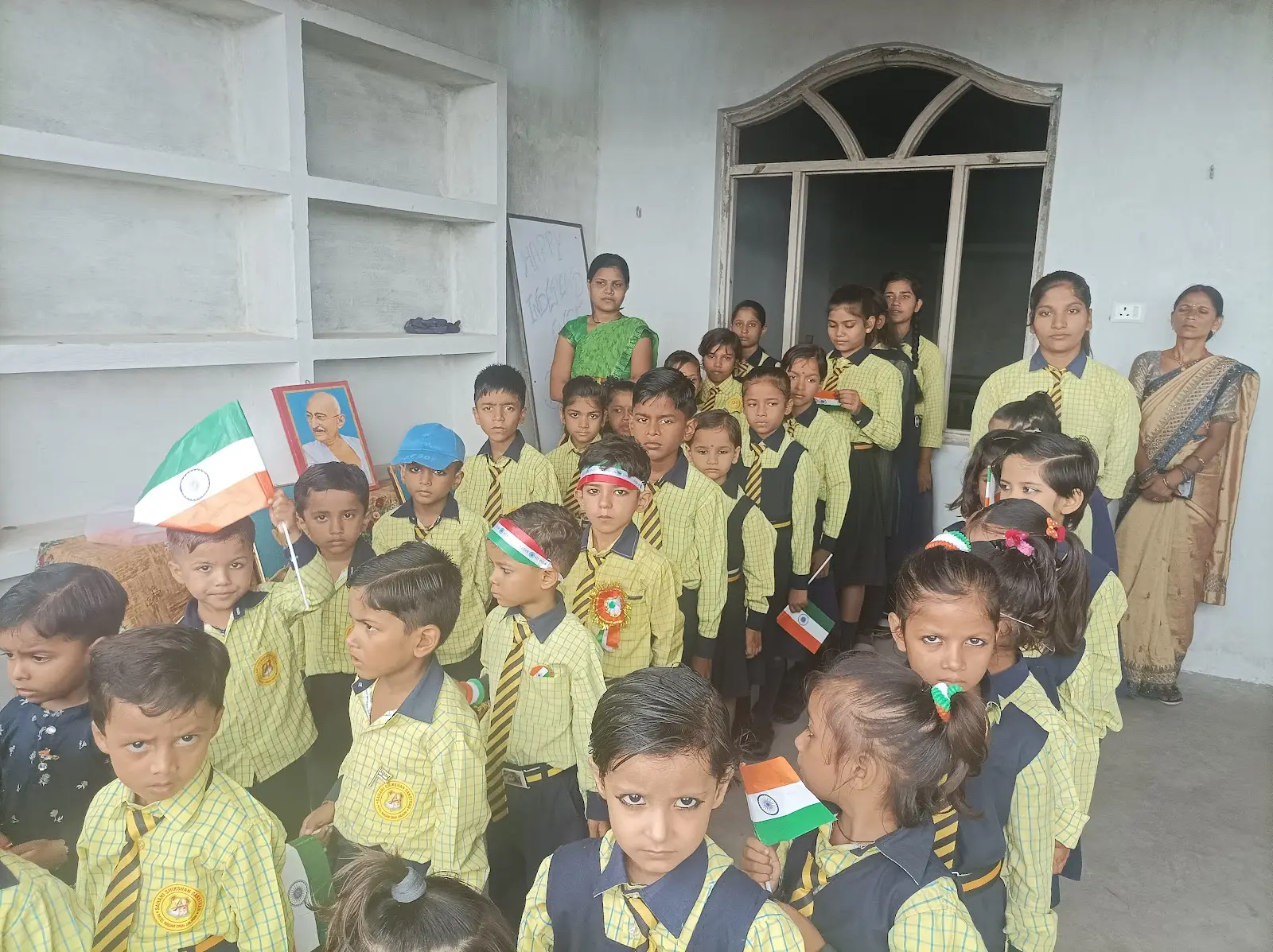 हाथों में तिरंगा लिए विद्यार्थी और शिक्षिकाएँ
